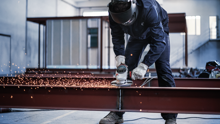 PRO Metal Grinding Disc, A 24 S BF, 180 x 6.6 x 22.23 mm, Depressed Centre A person wearing safety equipment grinds a metal beam, producing sparks.