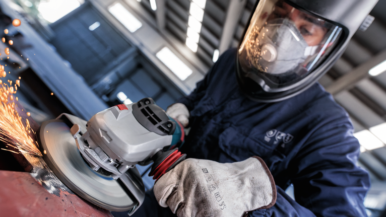 PRO Metal Grinding Disc, A 24 S BF, 180 x 6.6 x 22.23 mm, Depressed Centre A person wearing safety equipment grinds metal, causing sparks to fly.