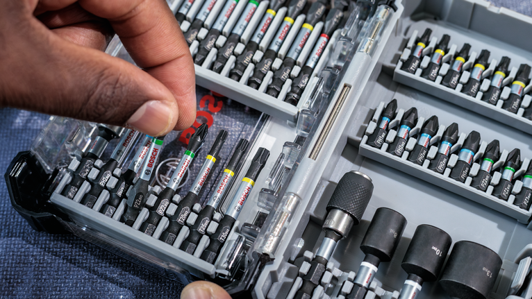 PRO PH Impact Bit, PH1 x 55, PH2 x 55, PH3 x 55 mm, 3 pcs Person selects a screwdriver bit from an organized tool kit.