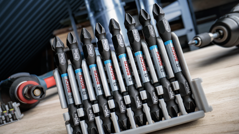 PRO PH Impact Bit, PH1 x 55, PH2 x 55, PH3 x 55 mm, 3 pcs Set of screwdriver bits organized in a plastic holder on a workbench.