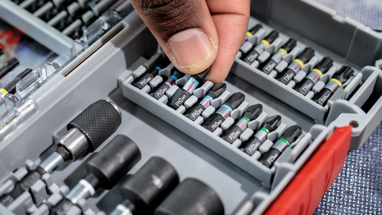 PRO PH Impact Bit, PH1 x 55, PH2 x 55, PH3 x 55 mm, 3 pcs Person selects a screwdriver bit from an organized tool case.