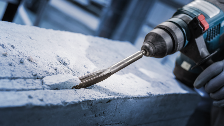 PRO SDS plus Hollow Gouging Chisel, 22 x 250 mm Person wearing safety equipment chiseling concrete with a rotary hammer.