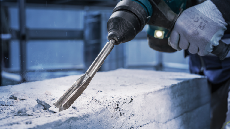 PRO SDS plus Hollow Gouging Chisel, 22 x 250 mm Person wearing safety equipment chisels concrete with a rotary hammer.
