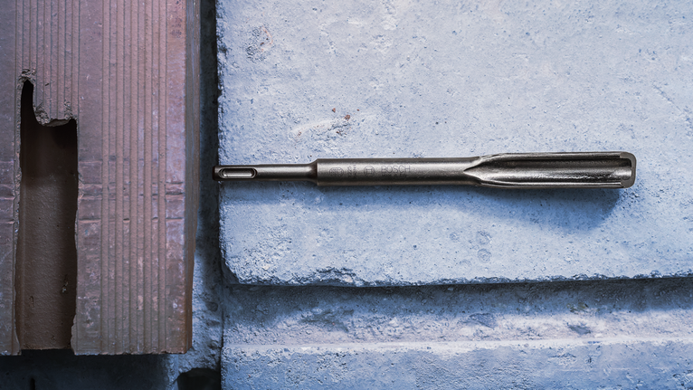 PRO SDS plus Hollow Gouging Chisel, 22 x 250 mm Chisel drill bit placed on a concrete block surface.