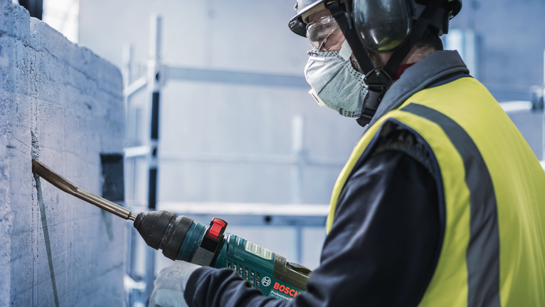 PRO SDS plus Hollow Gouging Chisel, 22 x 250 mm Person wearing safety equipment chiseling concrete with a power tool.