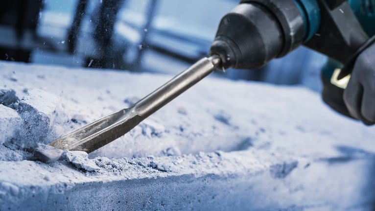 PRO SDS plus Hollow Gouging Chisel, 22 x 250 mm Person wearing safety equipment uses a rotary hammer to chisel concrete.