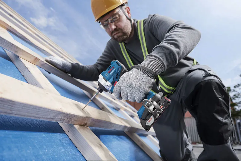 GDR 18V-215 A person wearing safety equipment uses a cordless drill to drive a screw into wooden beams.
