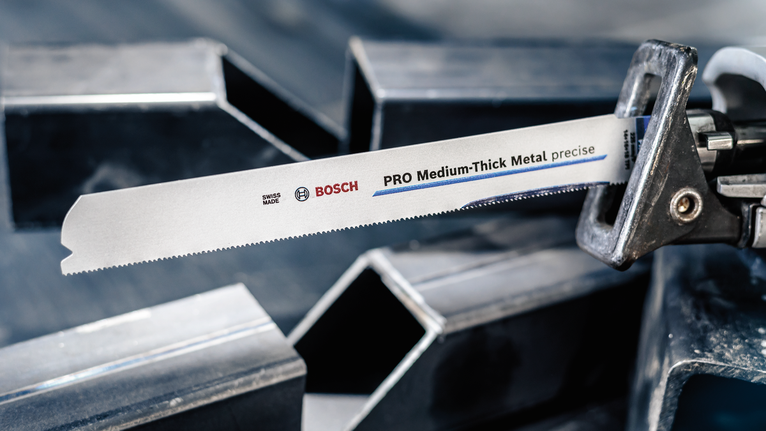 PRO Medium-Thick Metal precise S937BEF Blade, 1.1 x 25 x 150 mm, 5 pcs Reciprocating saw blade clamped in a saw, positioned near metal beams.