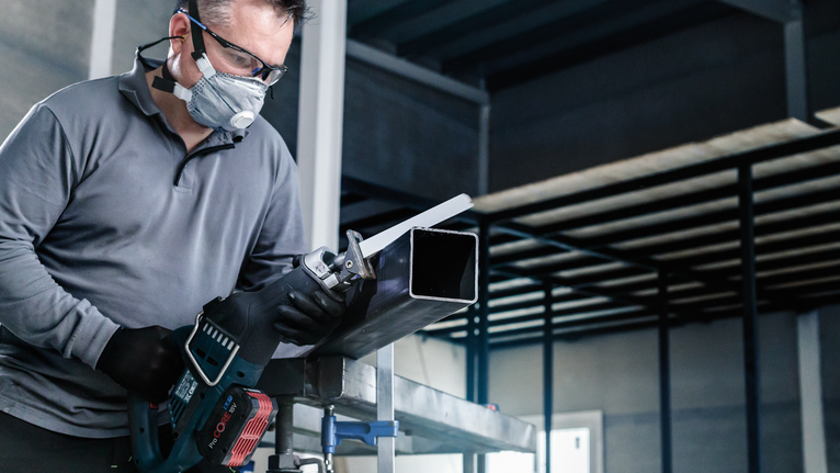 PRO Medium-Thick Metal precise S937BEF Blade, 1.1 x 25 x 150 mm, 5 pcs A person wearing safety equipment cuts a metal pipe with a reciprocating saw.
