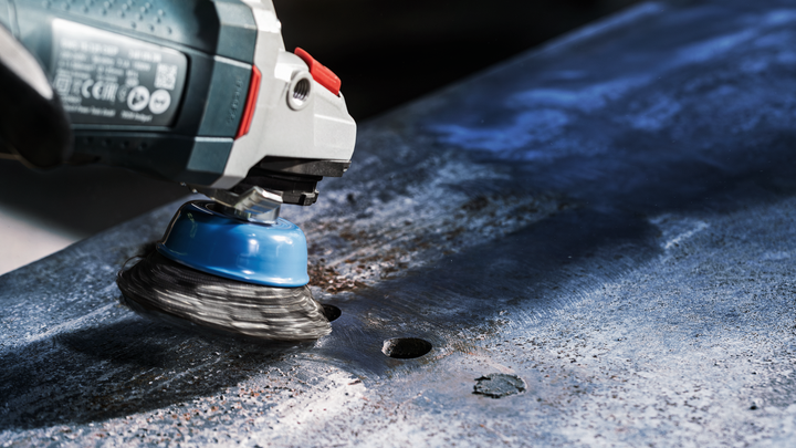 Object #200476267: 3089952_app_web_4 A power tool with a wire brush attachment cleans rust from a metal surface.