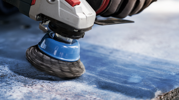 Object #200476268: 3089952_app_web_5 Person wearing safety equipment polishes a stone surface with a rotary brush tool.