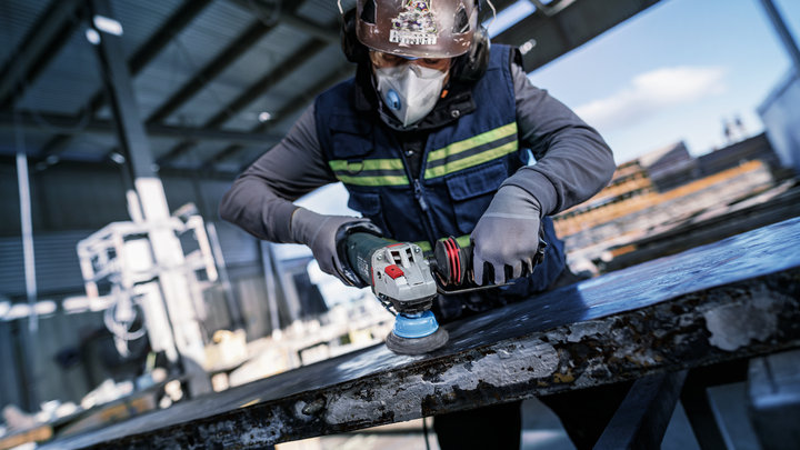 Object #200476269: 3089952_app_web_6 Person wearing safety equipment grinds metal surface with a power tool.