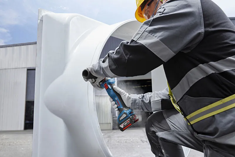 GWS 18V-11 S A person wearing safety equipment grinds a large metal pipe with a cordless angle grinder.