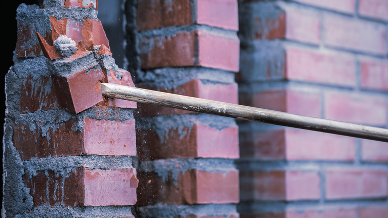 PRO SDS max-4C Pointed Chisel Set, 400 mm, 10 pcs Demolition bar breaking red bricks from a mortar wall.