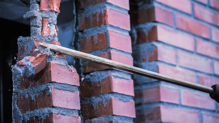 PRO SDS max-4C Pointed Chisel Set, 400 mm, 10 pcs Chisel tool breaking red brick wall during demolition.