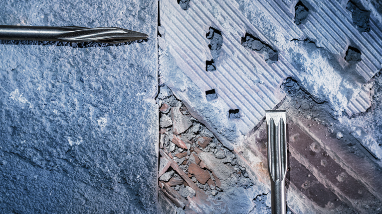 PRO SDS max-5C Flat Chisel, 25 x 400 mm Chisels breaking through a rough concrete and brick wall.