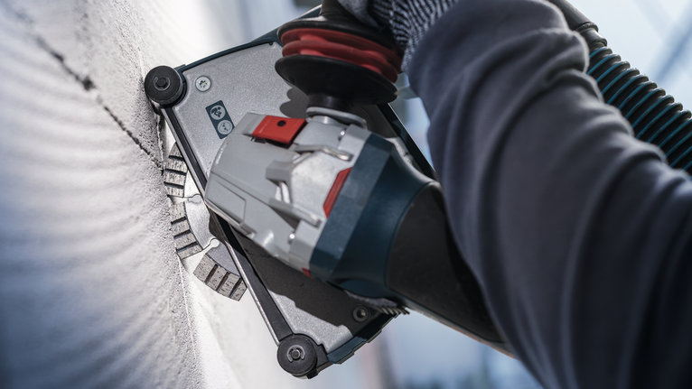 PRO Ceramic Diamond Disc, 105 x 20/16 mm Person wearing safety equipment grinds a wall with a power tool.