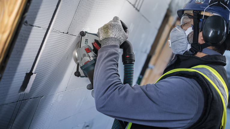 PRO Ceramic Diamond Disc, 105 x 20/16 mm A person wearing safety equipment uses a power tool to cut grooves into a wall.