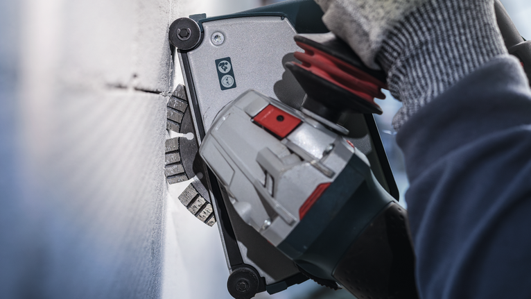 PRO Ceramic Diamond Disc, 105 x 20/16 mm Person wearing safety equipment uses a power tool to cut into a wall.