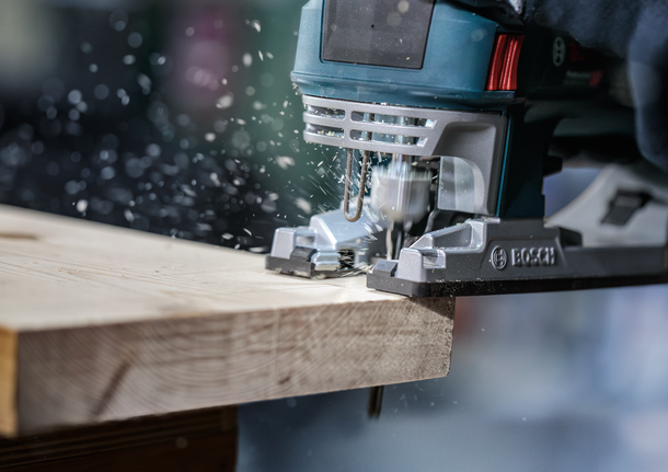 PRO Wood precise T144DP Jigsaw Blade, 100 mm, 5 pcs A person wearing safety equipment uses a jigsaw to cut through a wooden board.