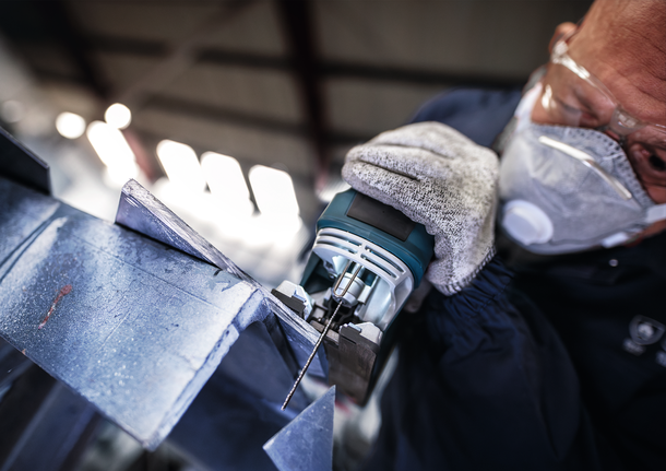 PRO Metal thick and thin T123XF Jigsaw Blade, 100 mm, 3 pcs Person wearing safety equipment uses a jigsaw to cut a metal sheet.