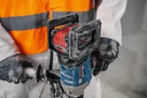 A person wearing safety equipment operates a cordless stirring mechanism.