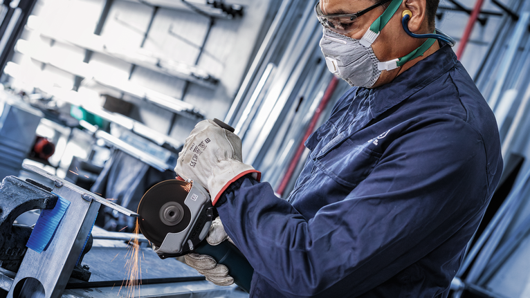 PRO Stainless Steel and Metal Bonded Cutting Disc, 125 x 1.6 x 22.23 mm, X-Lock, Straight, oSa A person wearing safety equipment grinds metal, producing sparks.