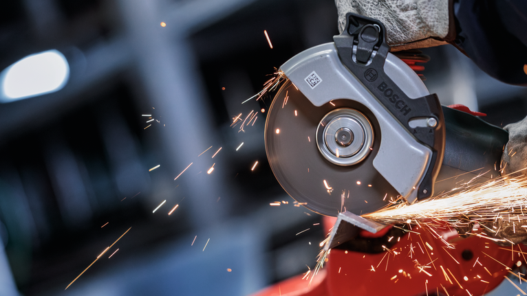 PRO Metal Bonded Cutting Disc, 125 x 1.6 x 22.23 mm, X-Lock A person wearing safety equipment grinds metal, producing bright sparks.