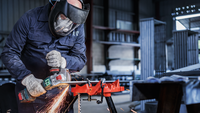 PRO Metal Bonded Cutting Disc, 125 x 1.6 x 22.23 mm, X-Lock Person wearing safety equipment uses a power tool to grind metal, creating sparks.