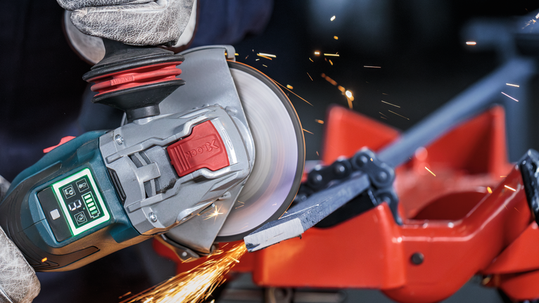 PRO Metal Bonded Cutting Disc, 125 x 1.6 x 22.23 mm, X-Lock Person wearing safety equipment uses an angle grinder to cut a metal bar.
