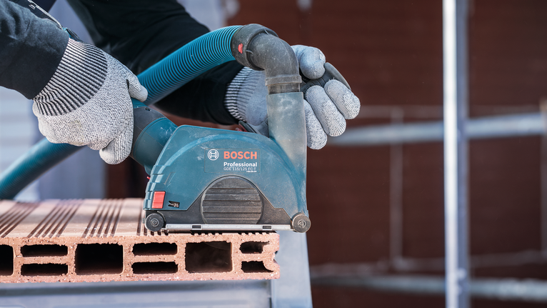 PRO Multi Material X-Lock Cutting Disc, 125 x 1 x 22.23 mm Person wearing safety equipment sands a brick block with a power tool.