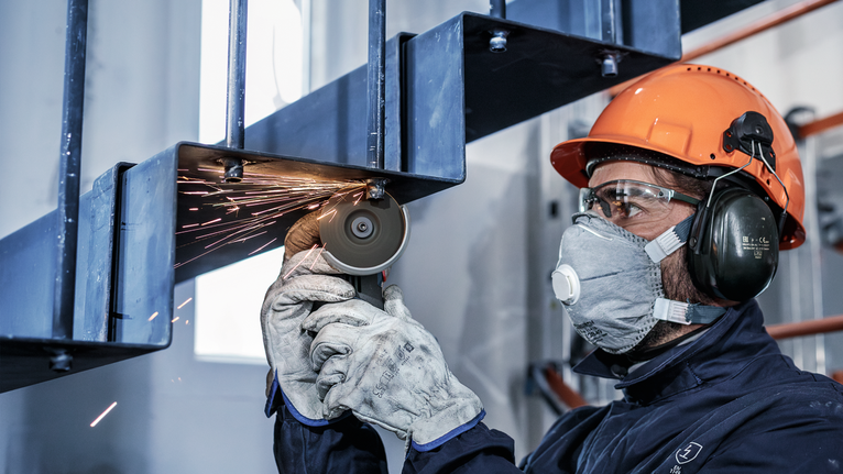 PRO Stainless Steel and Metal Grinding Disc, 76 x 4 x 10 mm Person wearing safety equipment cuts a metal staircase with a grinder.