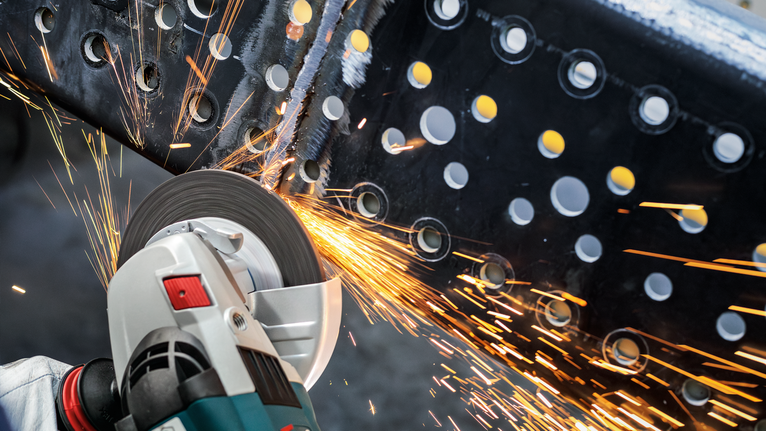 PRO Metal Grinding Disc, A 24 S BF, 180 x 6.6 x 22.23 mm, Depressed Centre Person wearing safety equipment grinds a metal beam with a power tool, creating sparks.