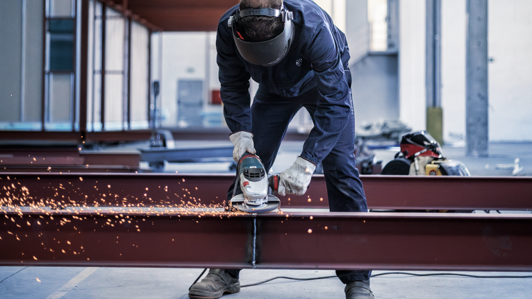 PRO Metal Grinding Disc, A 24 S BF, 180 x 6.6 x 22.23 mm, Depressed Centre Person wearing safety equipment grinds a steel beam, producing bright sparks.