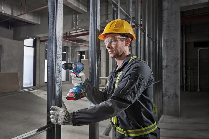 GSB 18V-65 A person wearing safety equipment drills into metal framing at a construction site.