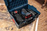 Cordless random orbit sander with battery and accessories stored in a blue case.