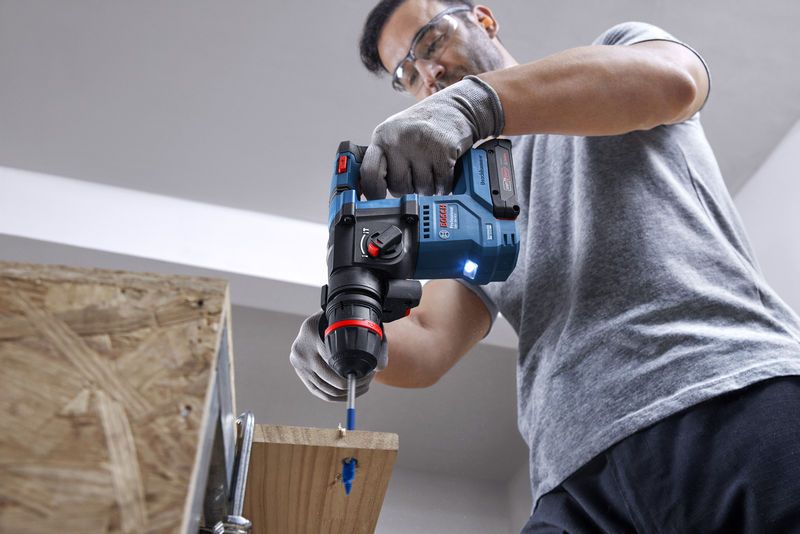 GBH 18V-18 X A person wearing safety equipment drills into wood with a cordless rotary hammer.