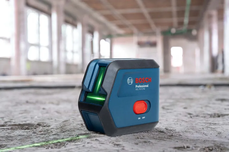 Laser leveling tool projecting green lines on a concrete floor in a construction site.