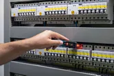 Person testing electrical panel with a non-contact voltage tester.