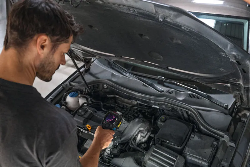 Person inspects a car engine using a thermal camera.
