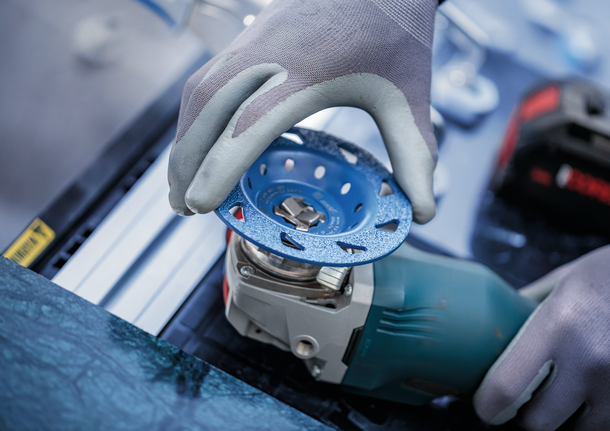 EXPERT Multi Material Carbide Grinding Head Medium, Flat, X-LOCK, 115 mm, 22.23 mm Person wearing safety equipment attaches a grinding disc to a power tool.