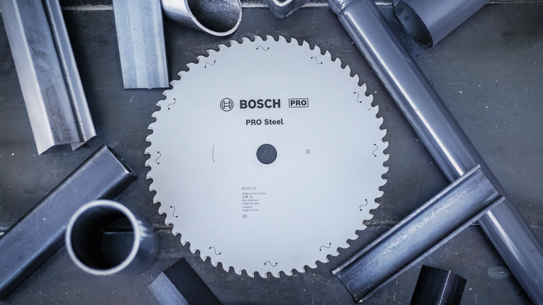 PRO Steel Circular Saw Blade, Corded, 254 x 2.2 x 25.4 mm, T52 Circular steel saw blade surrounded by metal pipes on a workbench.