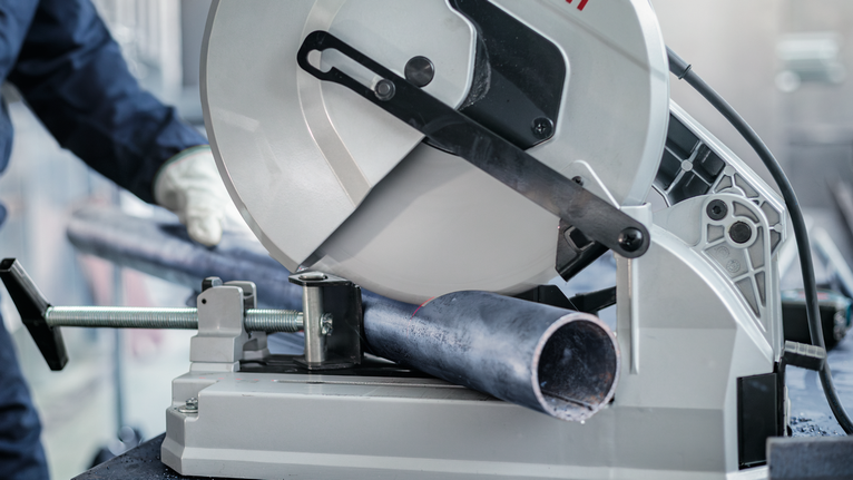 PRO Steel Circular Saw Blade, Corded, 254 x 2.2 x 25.4 mm, T52 A person wearing safety equipment cuts a metal pipe with a stationary saw.