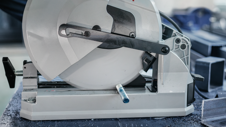 PRO Steel Circular Saw Blade, Corded, 254 x 2.2 x 25.4 mm, T52 Metal cutting saw positioned beside several angled steel bars.