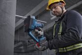 A person wearing safety equipment cuts a threaded rod with a cordless rod cutter.
