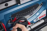 A person adjusts the angle gauge on a blue table saw.