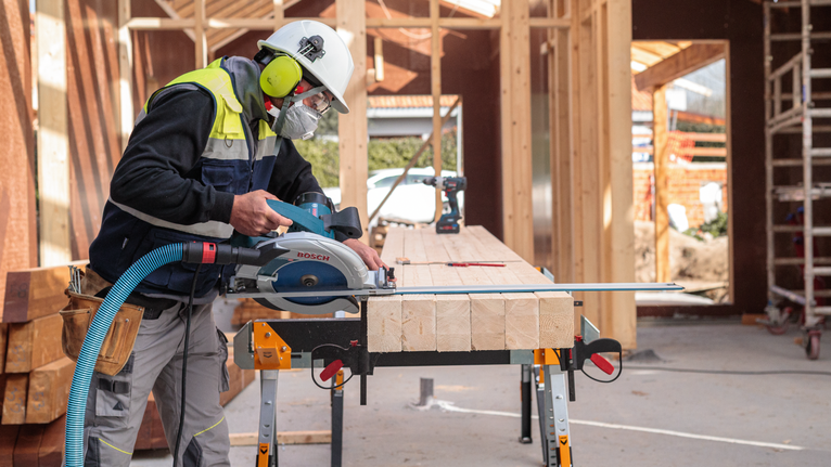 EXPERT Wood Circular Saw Blade, 165 x 2.6/1.6 x 20 mm, T24 Person wearing safety equipment cuts wood beams with a circular saw at a construction site.