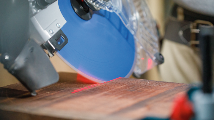Object #200585321: 7557711_app_web_07 Circular saw with a blue blade making a precise cut along a red laser guide on wood.