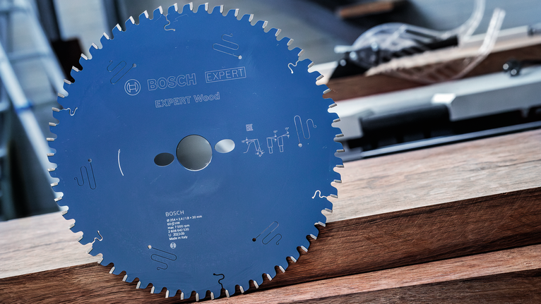 Circular saw blade positioned upright on stacked wooden planks.