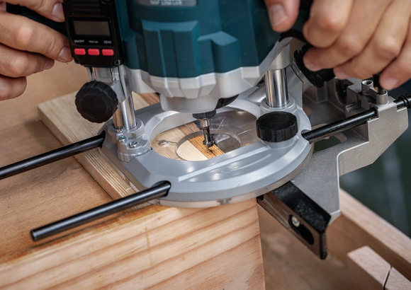 Person using a plunge router to cut a groove in a piece of wood.
